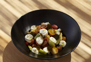 The famous cherry tomatoes creatively served in a dakos salad, is definitely among the top things on what to eat in Santorini.